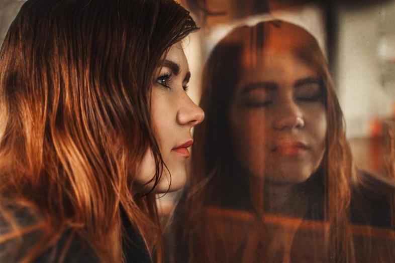 Henkilö katsoo oikealle. Heijastuksessa silmät ovat kiinni.