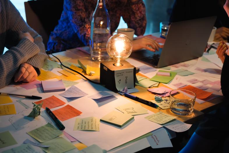 Pöydällä tarralappuja, keskellä hehkulamppu.