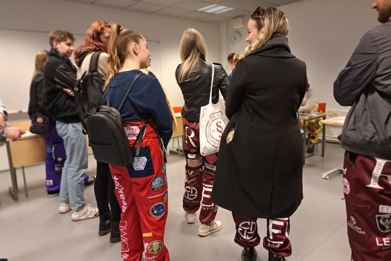 Haalareihin pukeutuneita opiskelijoita luokkahuoneessa.