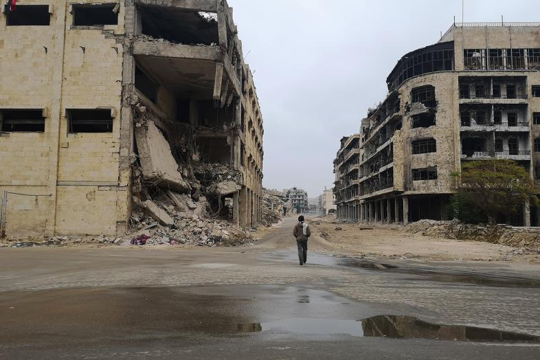 Ihminen kävelee sodan raunioissa kaupungissa.