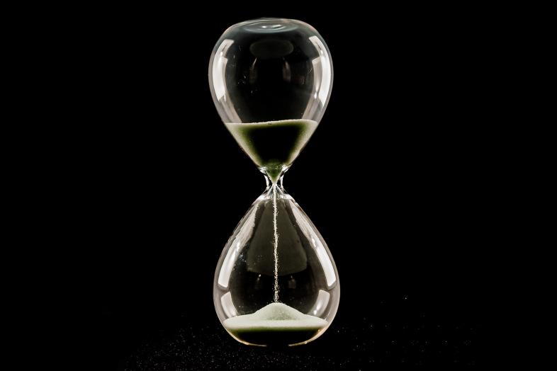 Tiimalasi mustaa taustaa vasten.