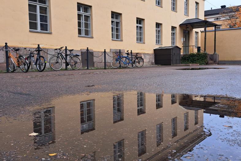 Topelia-rakennus heijastuu sisäpihan vesilammikosta.